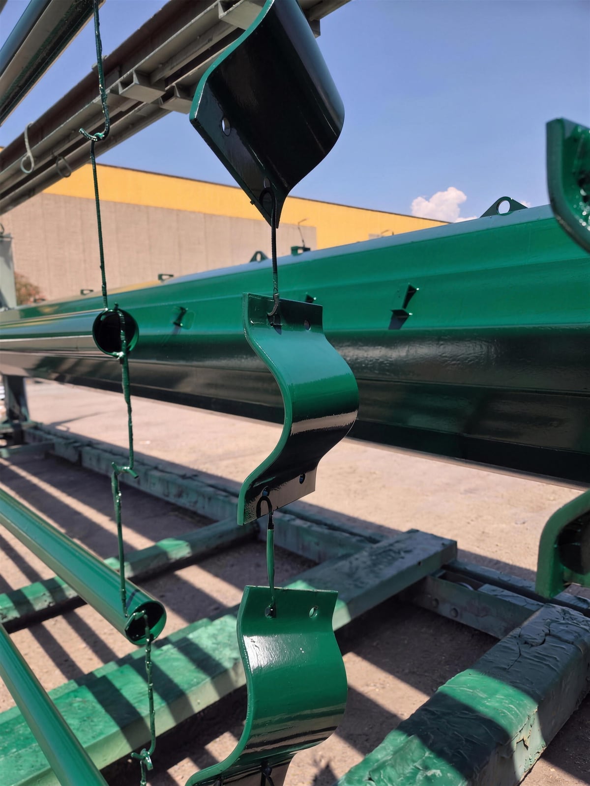 Collari e selle verniciate a polvere verde appese alle catene della linea