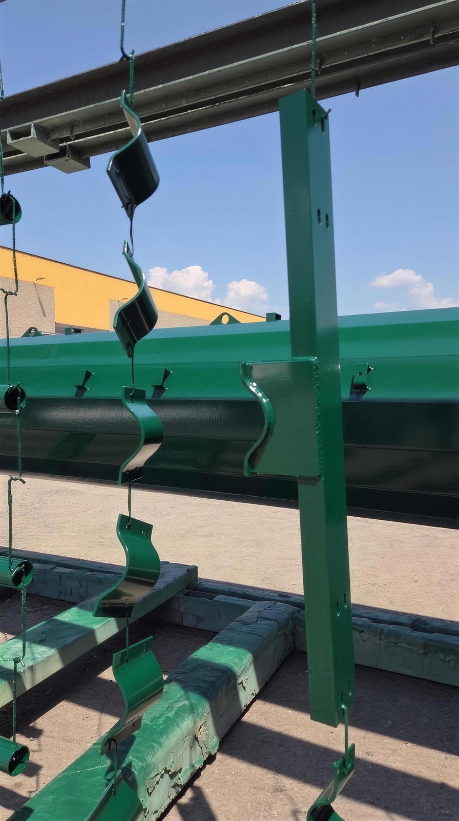 Mensola e collari verdi in primo piano con palo monotubolare sullo sfondo